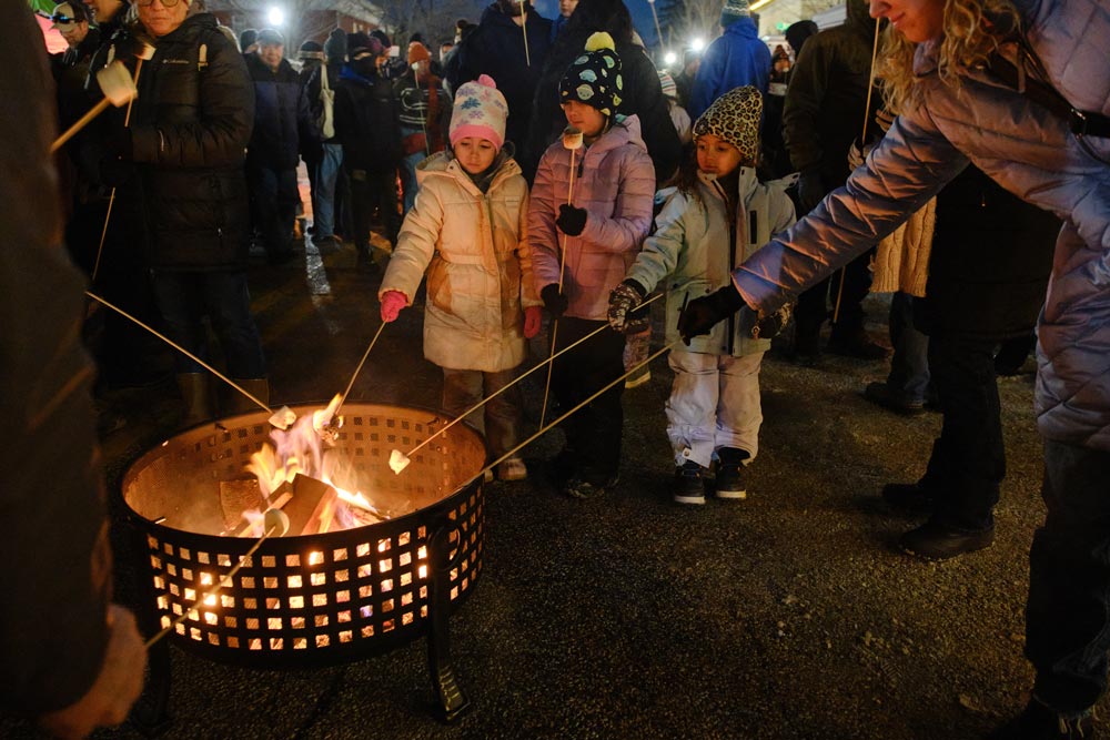 Kids and their families roasting marshmallows over a toasty outdoor fire